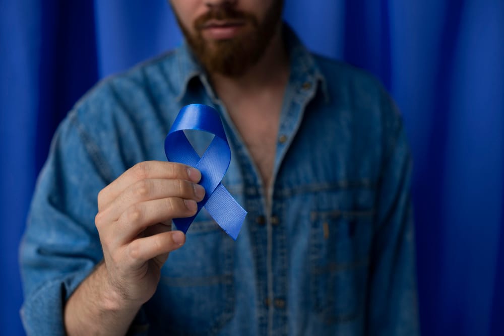 Movember - Main d’un homme tenant un ruban bleu, symbole de sensibilisation à la santé masculine